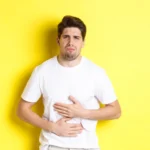 A person experiencing digestion issues due to unhealthy eating habits, stress, and poor lifestyle choices
